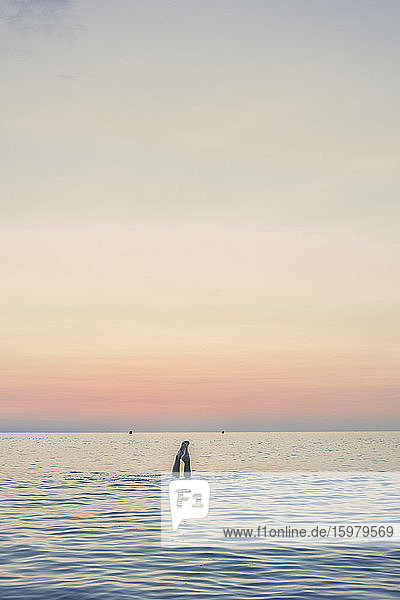 Füße eines Mädchens beim Tauchen im Meer bei Sonnenaufgang