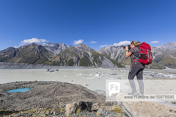 New Zealand  Oceania  South Island  Canterbury  Ben Ohau  Southern Alps (New Zealand Alps)  Mount Cook National Park  Tasman Glacier Viewpoint  Woman photographing Tasman Lake with ice floes