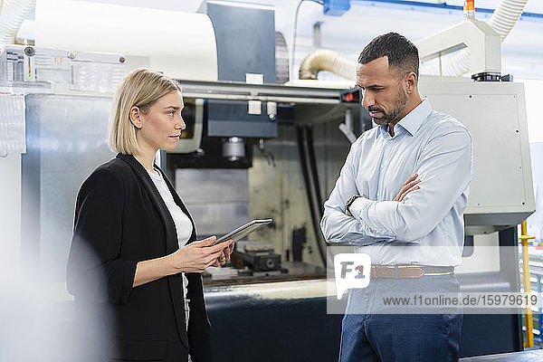 Businessman and woman with tablet in factory hall