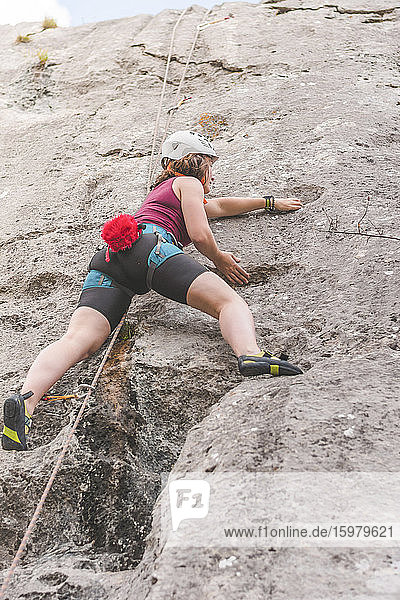 Young woman climbing rock
