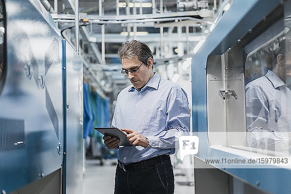 Mature businessman using tablet in a factory