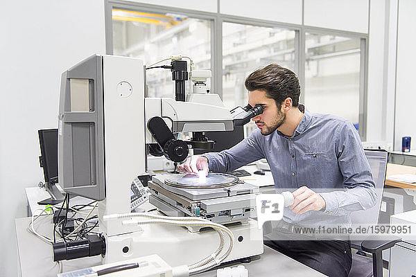 Man looking through microscope in a factory