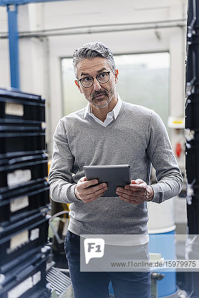 Thoughtful male supervisor holding digital tablet in factory