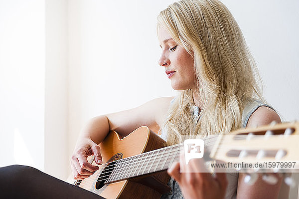 Portrait of blond woman playing guitar