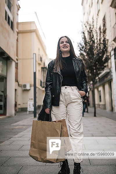 Porträt einer glücklichen jungen Frau mit Einkaufstüten in der Stadt