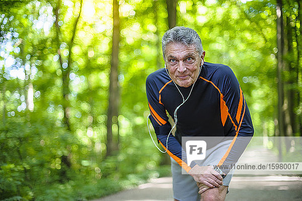 Lächelnder älterer Mann  der im Park trainiert und dabei wegschaut