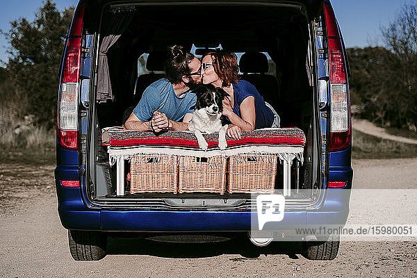 Pärchen mit Hund  das sich im Kofferraum eines Minivans küsst