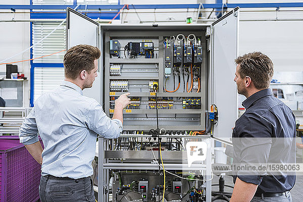 Two technicians working on circuit in factory