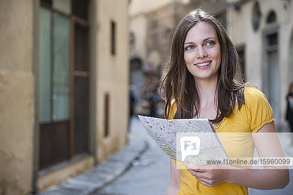 Porträt einer lächelnden Frau mit Stadtplan in einer Gasse  Florenz  Italien