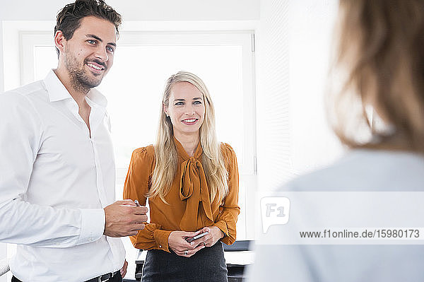 Happy male and female business colleagues discussing in office