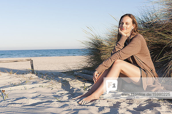 Portrait of smiling woman listening music with earphones on the beach  Sardinia  Italy