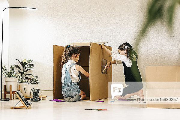 Zwei kleine Schwestern bauen Haus mit Karton
