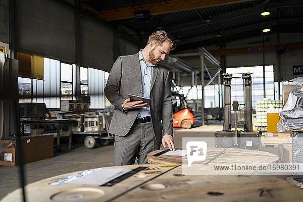Young businessman with tablet in a factory