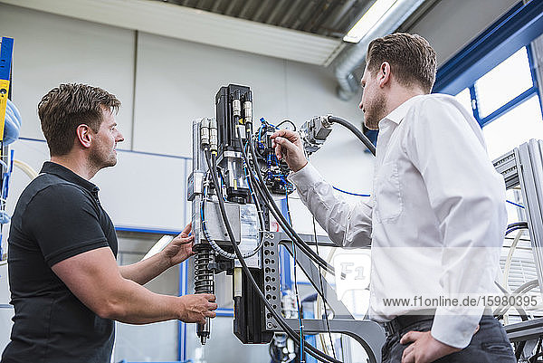 Zwei Männer bei einer Besprechung an einer Maschine in einer Fabrik