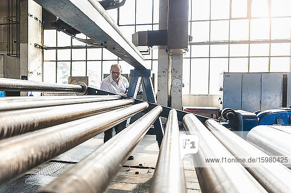 Senior businessman examining conveyor belt in a factory hall