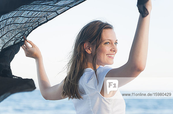 Porträt einer glücklichen Frau mit wehendem Tuch vor dem Meer  Sardinien  Italien