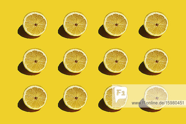 Pattern of fresh halved lemons against yellow background