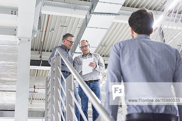 Three businessmen having a discussion in a factory