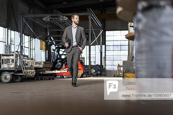 Young businessman with tablet walking in a factory