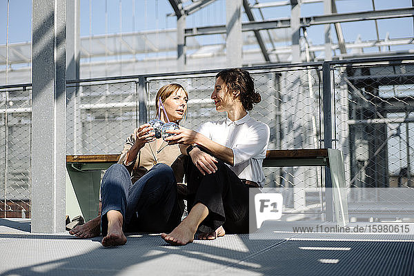 Zwei Geschäftsfrauen bei einem Drink an einer Metallkonstruktion im Freien