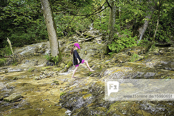 Volle Länge Seitenansicht von Mädchen zu Fuß barfuß auf natürlichen Bach im Wald