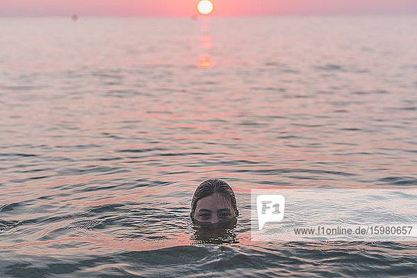 Porträt eines im Meer badenden Teenagers bei Sonnenaufgang
