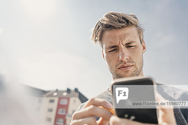 Junger Mann benutzt Smartphone auf dem Bacony