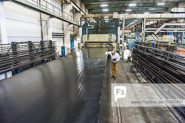 Senior businessman in a rubber processing factory examining product