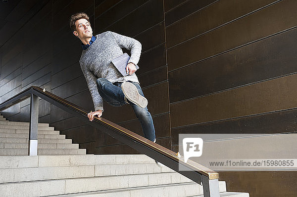 Junger Mann springt über das Geländer an der Treppe einer unterirdischen Gangway