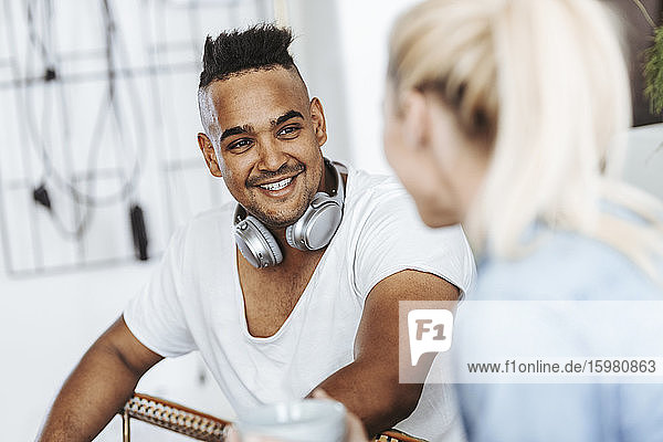 Porträt eines lächelnden Mannes mit Kopfhörern  der einem Freund zuhört