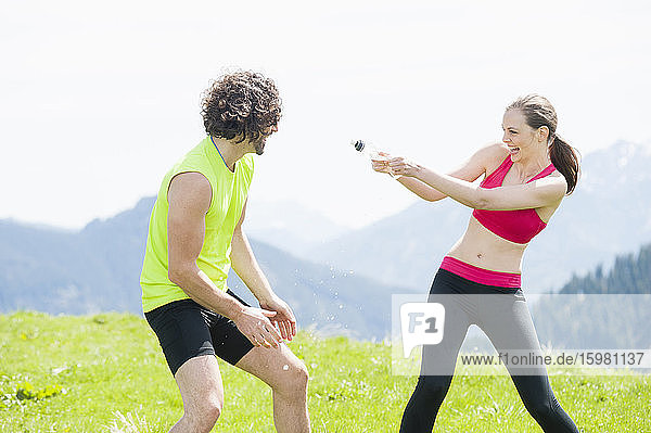 Female jogger squirting water to man  Wallberg  Bavaria  Germany