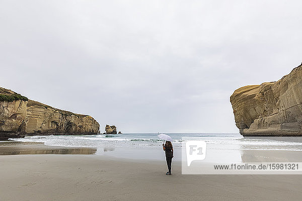 Neuseeland  Ozeanien  Südinsel  Otago  Dunedin  Frau mit Sonnenschirm am Tunnel Beach