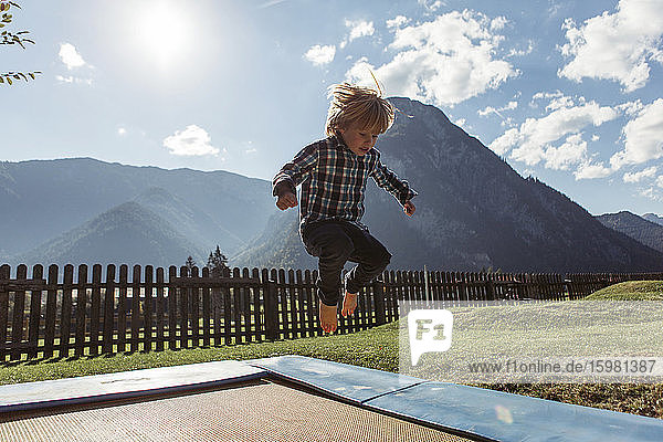 Boy jumping on boardwalk against mountains at Achensee  Tyrol State  Austria