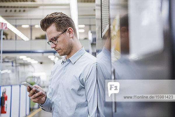 Businessman using smartphone in a factory