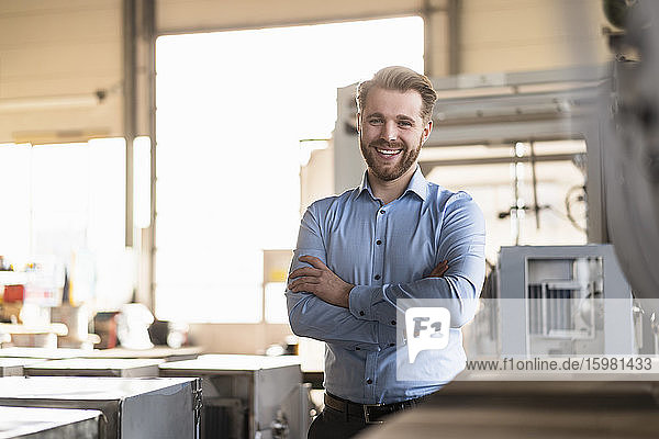 Portrait of a happy young businessman in a factory