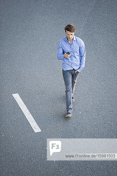 Geschäftsmann benutzt Smartphone beim Gehen auf der Straße