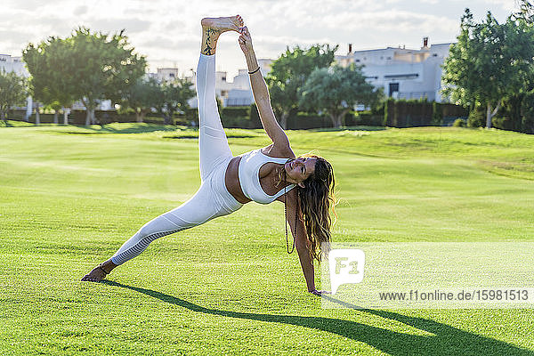 Frau macht Yoga auf Rasen im Sonnenschein