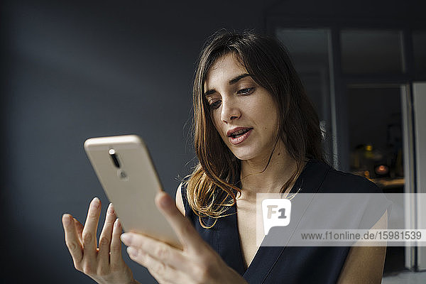Porträt einer jungen Frau  die auf ein Mobiltelefon schaut
