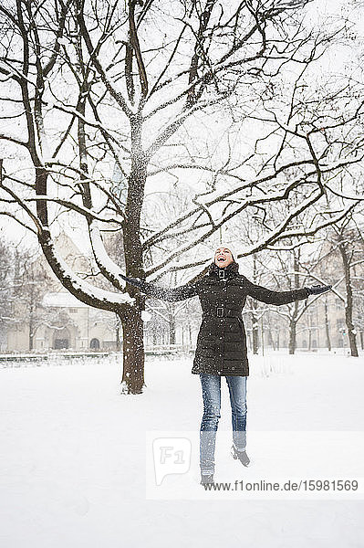 Lachende Frau  die Schnee in die Luft wirft