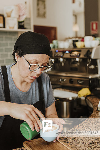 Porträt einer Kellnerin bei der Zubereitung von Cappuccino in einem Café