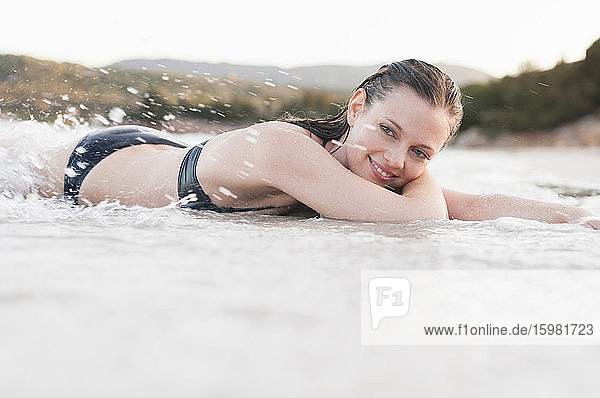 Porträt einer glücklichen Frau im Bikini  die sich am Meer entspannt  Sardinien  Italien