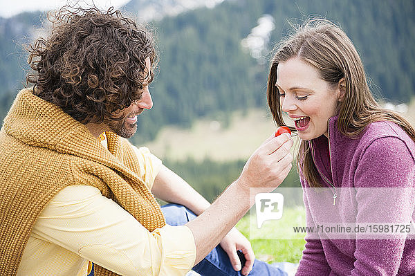 Glücklicher Mann füttert Frau beim Picknick mit Obst