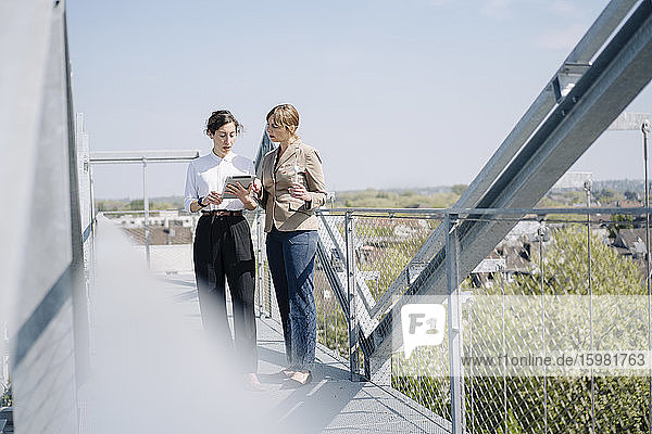 Zwei Geschäftsfrauen mit Tablet bei einem Treffen auf der Dachterrasse