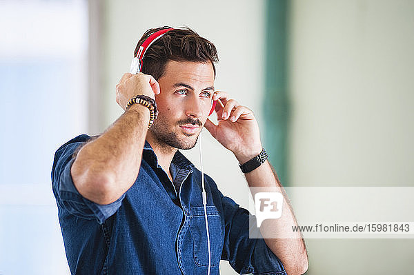 Porträt eines jungen Mannes  der mit Kopfhörern Musik hört