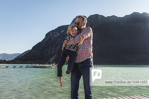 Vater küsst  während er seinen Sohn gegen einen Berg am Achensee trägt  Bundesland Tirol  Österreich