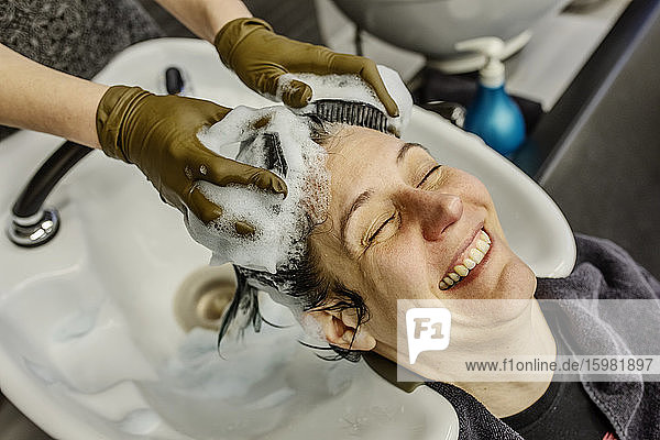 Woman in hair salon getting hair washed with brushes