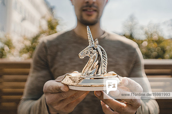 Young entrepreneur holding unicorn figurine  close up