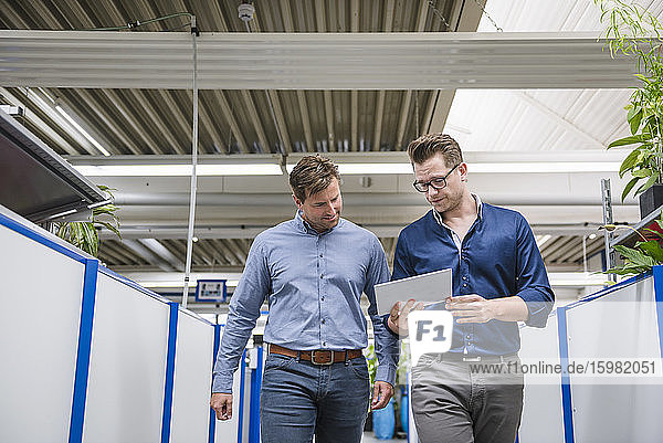 Two men with tablet talking in factory