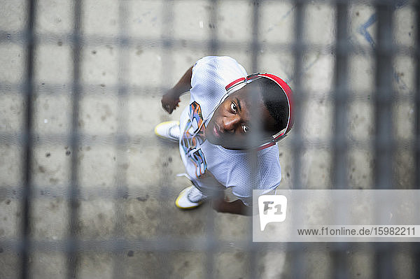 Young jogger with red headphones standing under grid and looking at camera