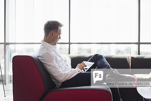 Geschäftsmann sitzt auf der Couch modernen Büro  mit digitalen Tablette